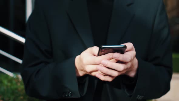 Young Caucasian Man Holding Smartphone Device Texting Sms Message Outside Business Office, Using