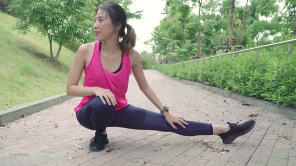 young Asian women legs and stretching her arms to ready for running on street in urban city park.