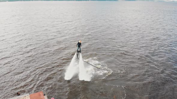 Water Sports  a Man Training Flying Over the Water on the Flyboard Near an Island  Aerial View