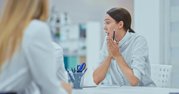 Young Business Woman in a White Shirt Sits in the Office and Talks to Colleagues About Development