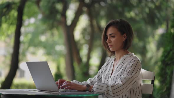 Business Woman Brunette Arabic Hispanic Ethnic Group is Typing on a Laptop While Sitting at a Table