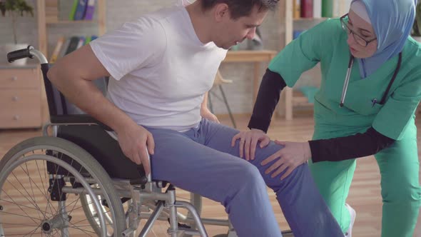 Close Up of Muslim Nurse in Hijab Helps Disabled Person To Get Up From Wheelchair