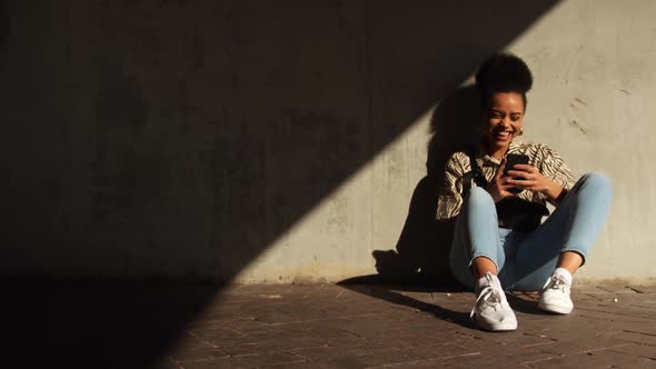 Mixed race woman laughing on smartphone under bridge