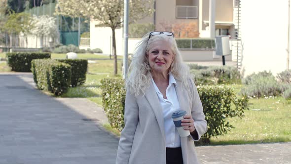 Mature businesswoman standing in city, holding coffee cup