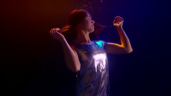 Calm Charming Woman Is Keeping Afloat Underwater in Darkness, Playing with Hair