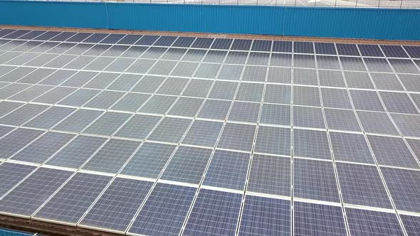 Aerial view of solar power plant with blue photovoltaic panels mounted of industrial building roof