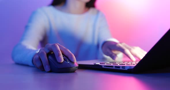 Woman using notebook computer with purple and blue light