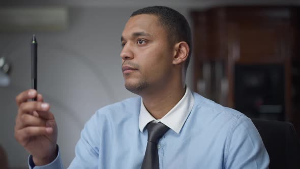 Young African American Man Doing Eye Exercises and Looking at Camera Sitting in Home Office Indoors