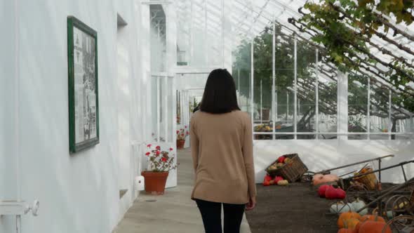 Young Woman Walking Through Greenhouse