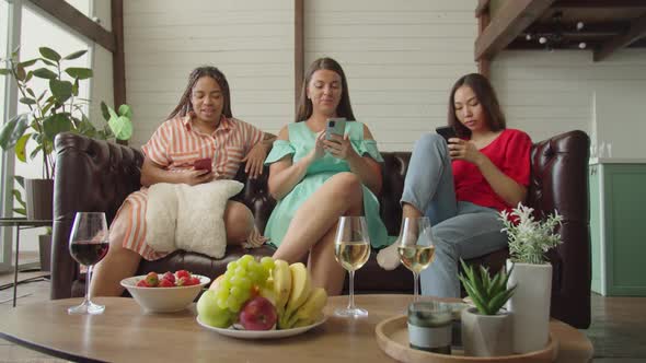 Mixed Race Young Women Looking Into Phones Surfing Internet Indoors