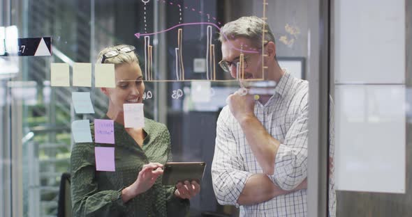 Video of happy caucasian female and male designers brainstorming in office