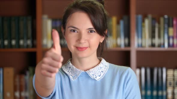 Portrait of Smiling Beautiful Pretty Woman and Doing Thumb Up in Library Office Bookshelf Background