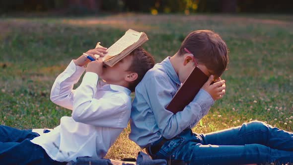 Young Guys in Shirts Sleep with Books in Hands in Garden