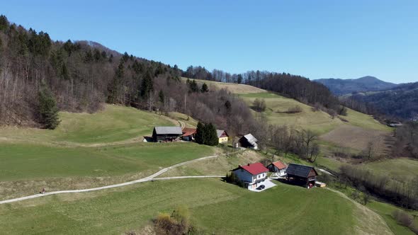 Rustic houses on the hills surround by forest and mountains. Aerial view