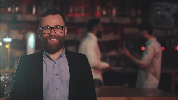 Portrait of Smiling Attractive Man Wearing Glasses Looking at Camera in a Bar or Beer Pub. Concept