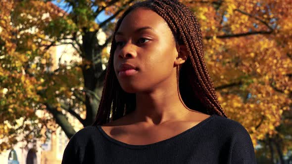 Young Beautiful Black Woman Looks Around in the Park in Autumn Day - Closeup