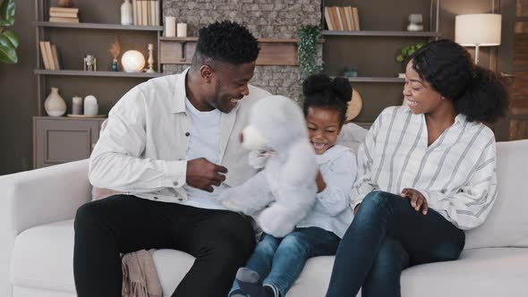 African Happy Family Parents with Child Daughter Sitting on Sofa at Home Having Fun Sincerely