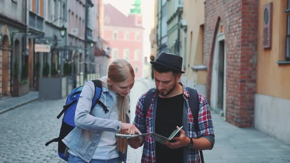 Two Young Tourists Checking Map While Walking on Main Tourist Street