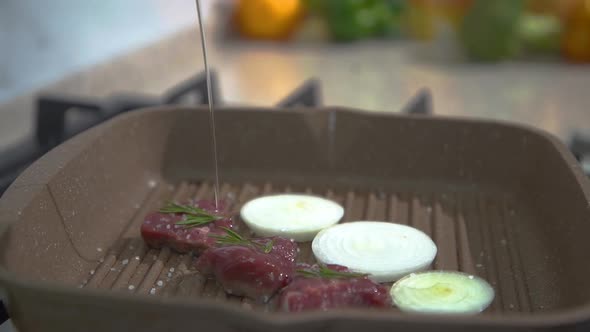 Cook adds oil to the meat in the pan