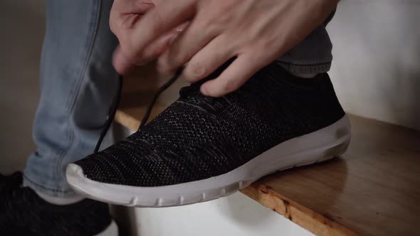 Closeup of One Person's Feet Tying Shoelaces or Shoestrings Up at Home Stairs