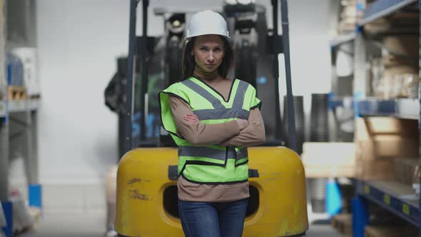 Gorgeous Slim Caucasian Woman Standing at Forklift Crossing Hands Looking at Camera with Serious