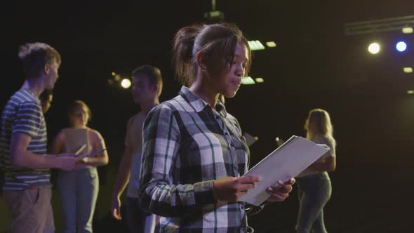 Students preparing before a high school performance in an empty school theater 