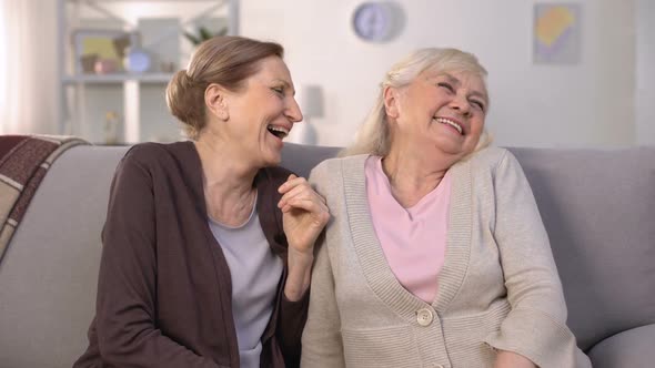 Senior Ladies Laughing Out Loud, Telling Funny Stories Sitting on Couch at Home