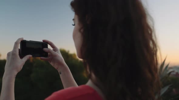 Young adult woman taking picture on mobile phone in Barcelona