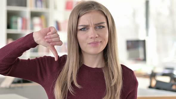 Portrait of Disappointed Young Woman with Thumbs Down