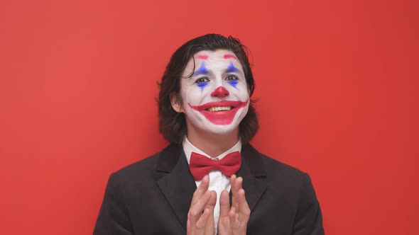 Portrait of a Strange Clown in a Suit on an Isolated Red Background