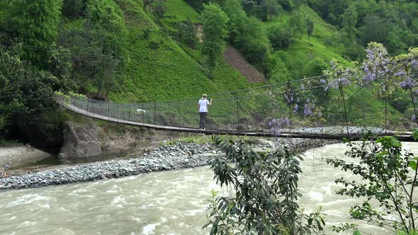 Woman Watching the River from Rope Bridge