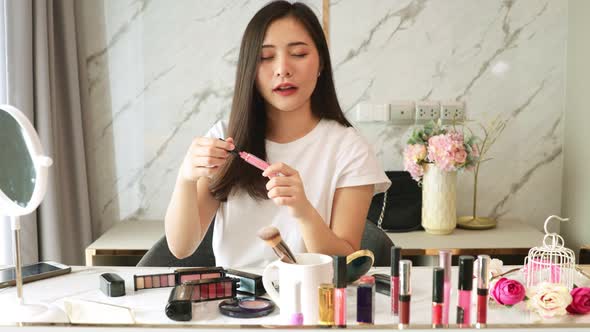 Portrait of young asian woman review cosmetics prosduct