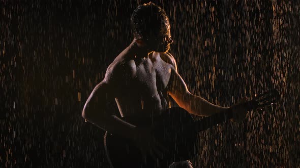 Silhouette of Man with Naked Torso Holding Acoustic Wooden Guitar in His Hands