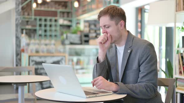 Young Man with Laptop Having Coughing