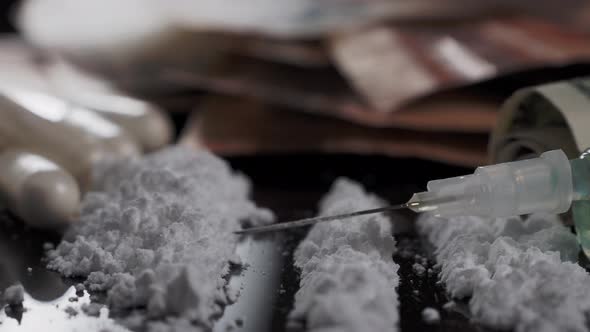 Money and drugs on a black glass table. Money, syringe and drugs.