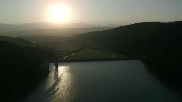 Wide aerial view of reservoir behind dam above scenic valley in Romania. Sunset