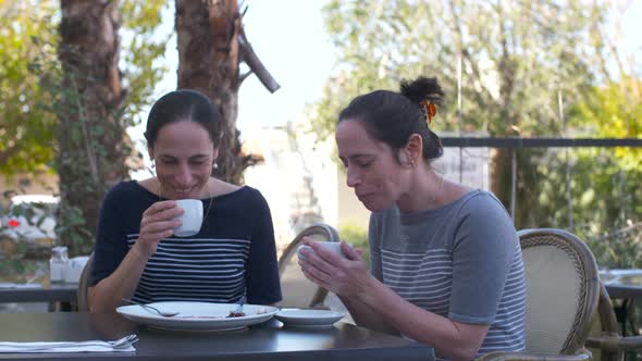 Two Caucasian female identical twins sitting together at a cafe