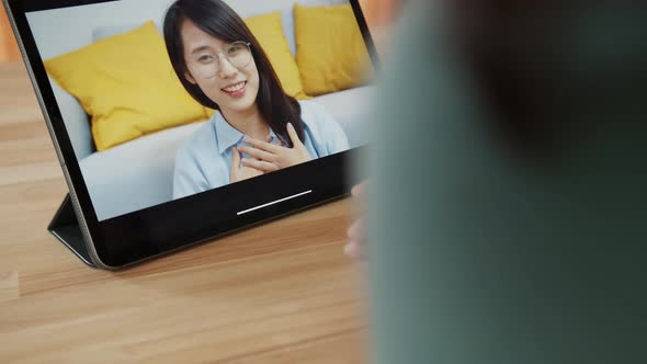 Over the shoulder shot of Asian woman video calling on tablet