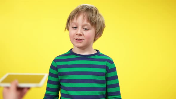 Portrait of Excited Little Boy Looking at Stretched Tablet and Smartphone with Toothy Smile