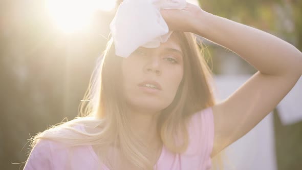 Closeup Exhausted Young Housewife in Sunbeam Rubbing Forehead Looking at Camera