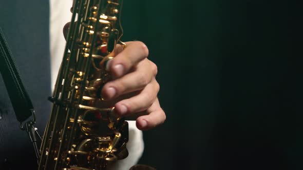 Professional Musician Fingering Keys Playing Golden Shiny Saxophone on Stage. Dark Studio with Smoke