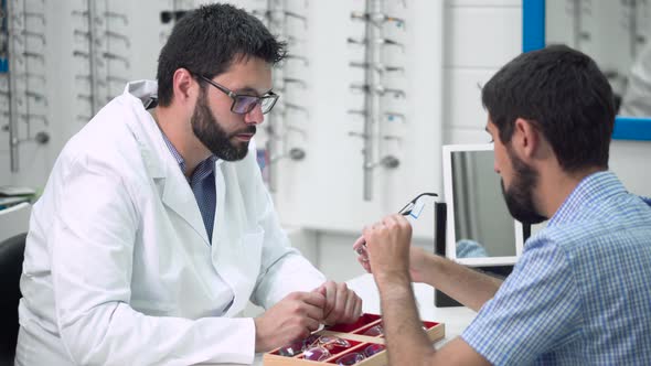 Doctor Ophthalmologist Is Helping a Client To Choose the Most Appropriate Glasses in Ophthalmologic