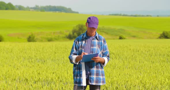 Male Farmer Analyzing Wheat While Making Report