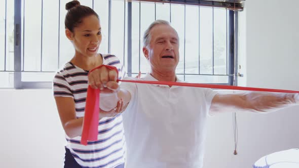 Physiotherapist helping patient in performing exercise with resistance band 4k