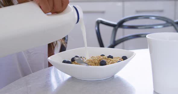 Man pouring milk in a bowl at kitchen 4k