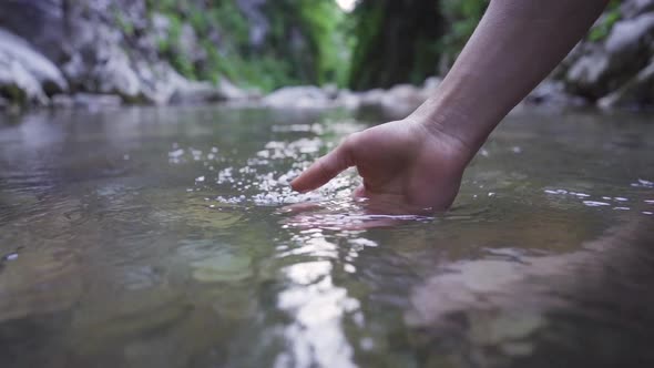 Putting your hand in clean and clear stream water.