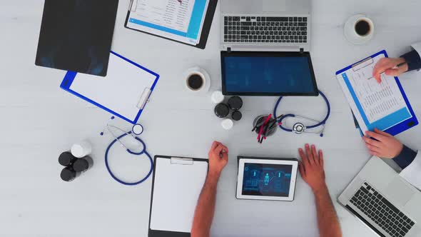 Top View of Physicians in Meeting with Reports and Laptop