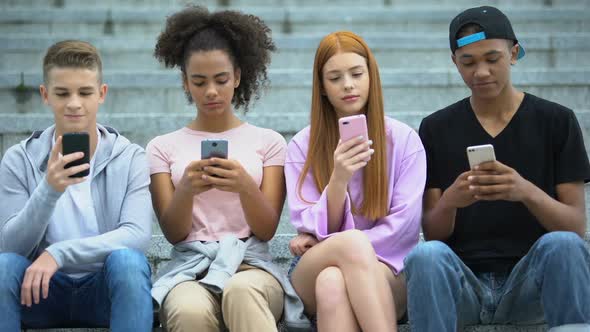 Teenage Group of Friends Sitting on Stairs and Chatting Smartphone, Addiction