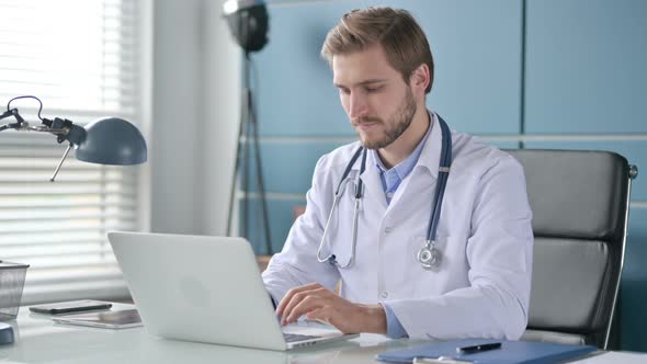 Doctor Pointing at Camera While Using Laptop in Clinic