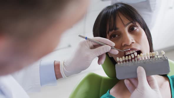 Caucasian male dentist examining teeth of female patient at modern dental clinic